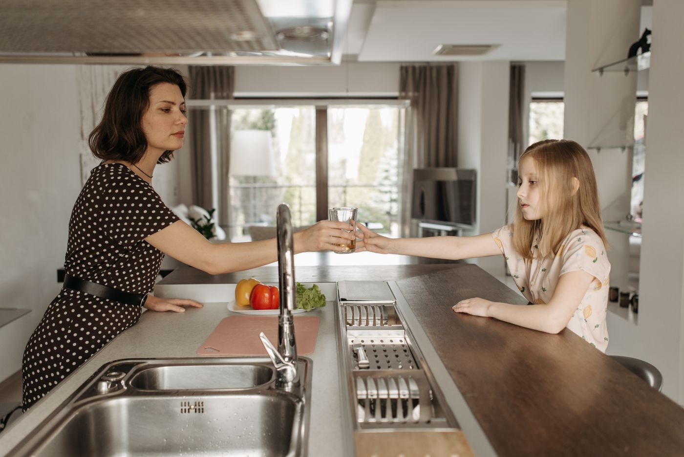 Mother and daughter sharing a glass of clean water in their kitchen